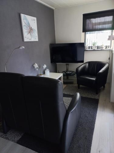 De Wilp的住宿－Appartement Ons Plekje，客厅配有黑色家具和平面电视