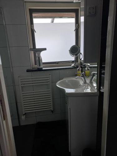 een badkamer met een wastafel en een raam bij Appartement Ons Plekje in De Wilp