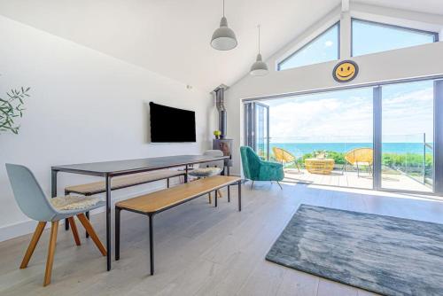 a living room with a table and chairs and a large window at Seafire Beach House - West Wittering in West Wittering