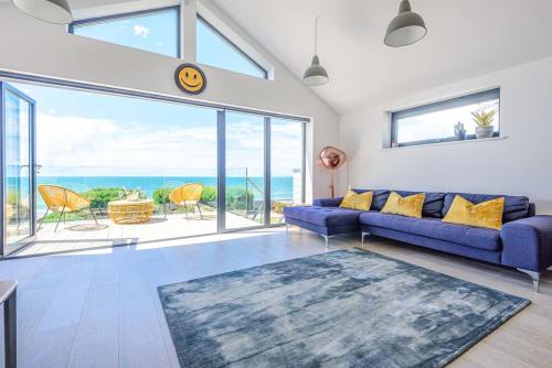 a living room with a blue couch and a large window at Seafire Beach House - West Wittering in West Wittering