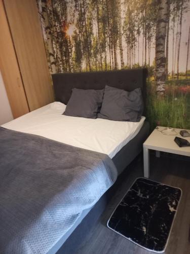 een bed in een kamer met een muur met bomen bij Appartement Ons Plekje in De Wilp