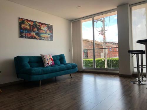uma sala de estar com um sofá azul e uma grande janela em Espectacular apartamento con estacionamiento gratuito Chía N 2 em Chía