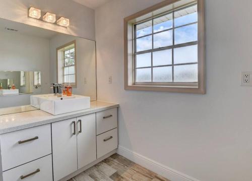 a white bathroom with a sink and a mirror at 5 BR Mansion with Pool and non-heated Jacuzzi Games in Boynton Beach in Boynton Beach
