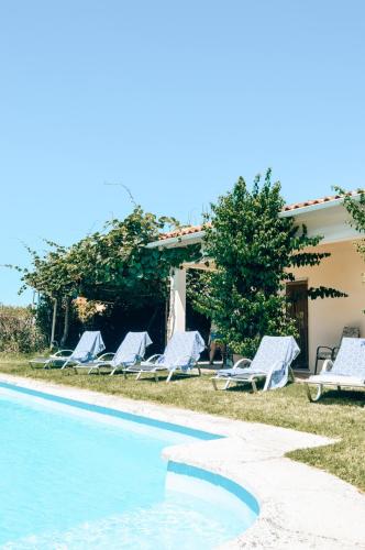 a group of lounge chairs next to a swimming pool at Just Like Home - Casa do Sobreiro Velho em Cerveira in Vila Nova de Cerveira