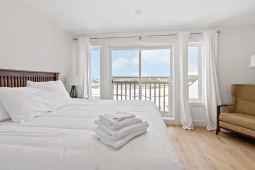 a white bedroom with a bed with towels on it at Rivergrass Home with Mountain and Golf Course Views in Blue Mountains