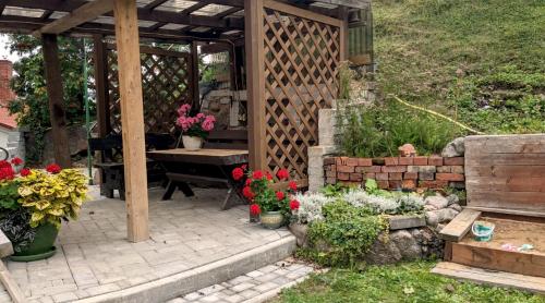 Talsi 2 rooms and backyard في تالسي: حديقة فيها بريغولا خشبي وبعض الزهور