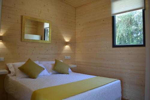 sypialnia z łóżkiem w drewnianej ścianie w obiekcie Cabañas Compostela - Cabaña Bosque Encantado w Santiago de Compostela