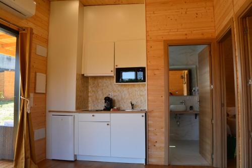uma cozinha com armários brancos e uma porta de vidro deslizante em Cabañas Compostela - Cabaña Bosque Encantado em Santiago de Compostela
