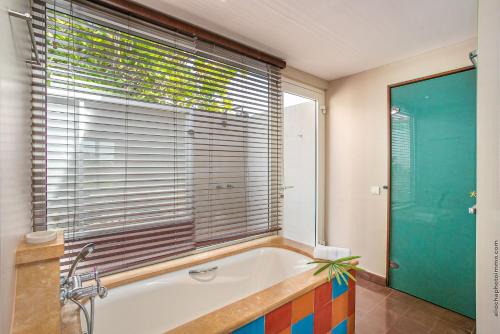 a bathroom with a tub and a large window at Les Villas du Lagon in Le François