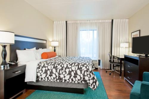 a hotel room with a bed and a desk and a television at Hotel Indigo Atlanta Airport College Park by IHG in Atlanta
