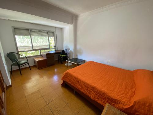 1 dormitorio con cama de color naranja y escritorio en piso para jovenes familia cerca playa y centro . BLASCO IBANEZ A en Valencia