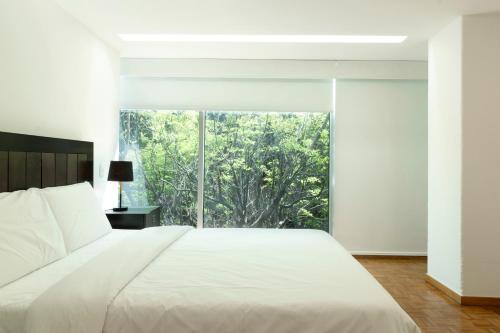 a bedroom with a large bed and a large window at Balsas By HomiRent in Mexico City
