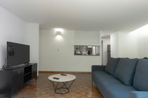 a living room with a blue couch and a tv at Balsas By HomiRent in Mexico City