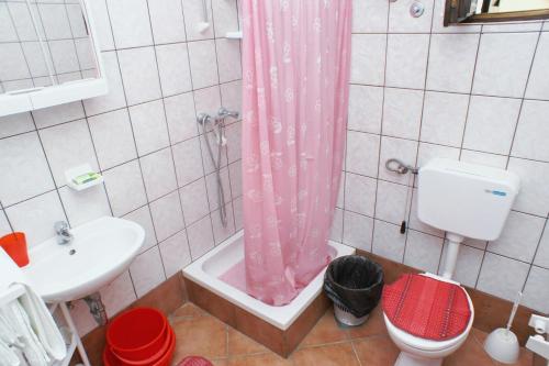 a bathroom with a pink shower curtain and a toilet at Apartment Mandre 523b in Kolan