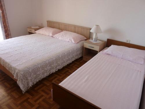 two beds in a bedroom with two tables and a lamp at Apartment Metajna 525d in Zubovići