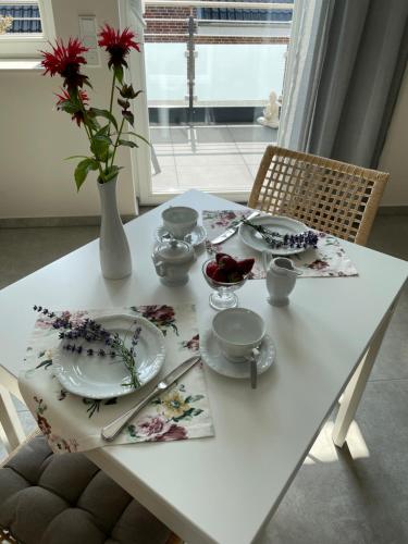 a white table with dishes and a vase with flowers on it at Studio - Apartment Steinmetz mit Balkon in Reken