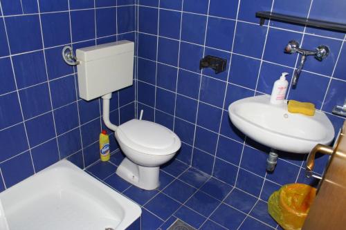 a blue tiled bathroom with a toilet and a sink at Apartments by the sea Podgora, Makarska - 518 in Podgora