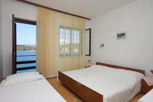 a bedroom with two beds and a large window at Apartments by the sea Luka, Dugi otok - 441 in Luka