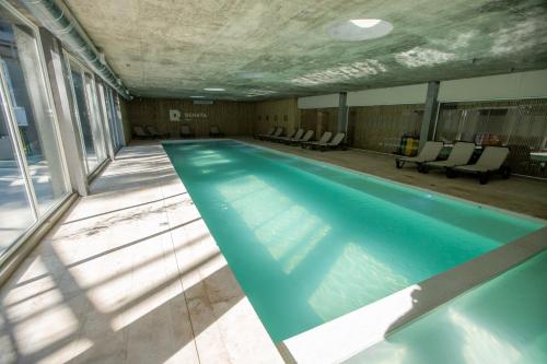 a swimming pool in a building with chairs at 3 ambientes en Complejo de Lujo in Pinamar