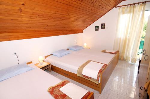 1 dormitorio con 2 camas y techo de madera en Apartments by the sea Basina, Hvar - 542 en Vrbanj