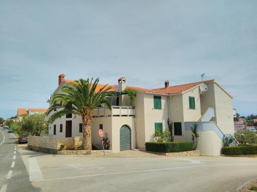 a house with a palm tree in front of a street at Apartments by the sea Sali, Dugi otok - 444 in Sali