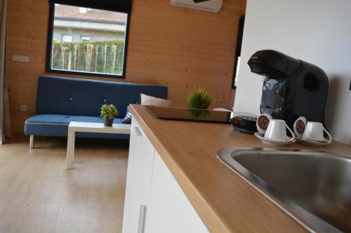 a kitchen with a sink and a blue couch at Cabañas Compostela - Cabaña A Fervenza in Santiago de Compostela