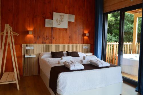 1 dormitorio con 1 cama con toallas en Cabañas Compostela - Cabaña Pedroso con bañera de hidromasaje, en Santiago de Compostela