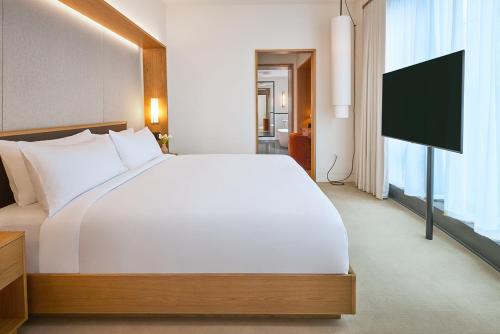 a bedroom with a white bed and a flat screen tv at Pendry Manhattan West in New York