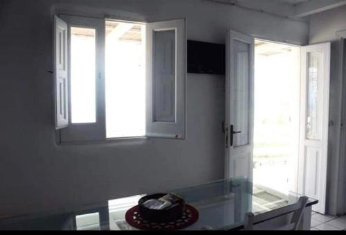 cocina con mesa de cristal y 2 ventanas en Casa Vacanze sul mare, en Malfa
