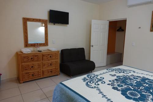 a bedroom with a bed and a chair and a mirror at Quinta Comala Hotel & Villas in Comala