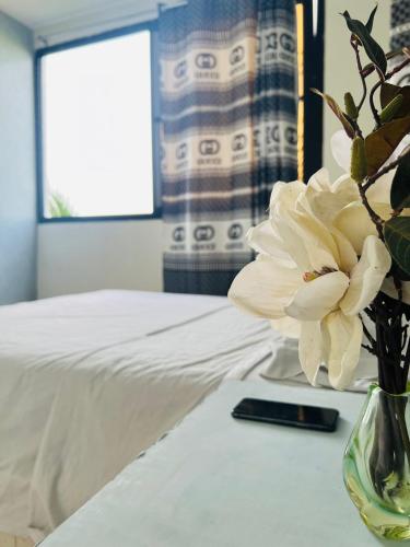 a vase with a flower on a table next to a bed at keur manga2 in Somone