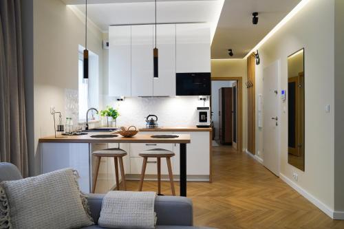 a kitchen with white cabinets and a kitchen island with stools at Toruńskie Zacisze 5 in Toruń