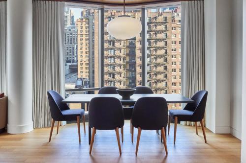 a dining room with a table and chairs and a large window at Pendry Manhattan West in New York