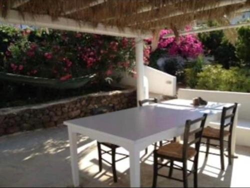 una mesa blanca y sillas en un patio con flores en Casa Vacanze sul mare, en Malfa