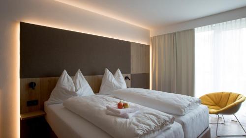 Hollenstein an der YbbsにあるObstgarten Gästehausの白いベッド2台と椅子が備わるホテルルームです。