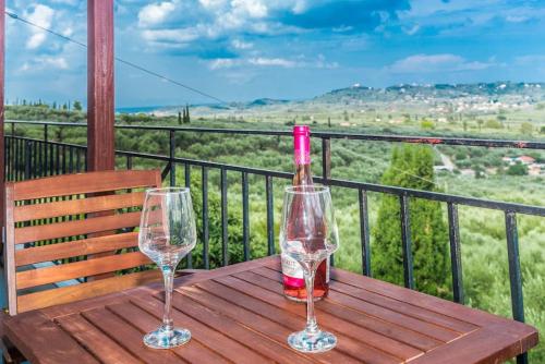 2 copas de vino sentadas en una mesa de madera en un balcón en Sohoro house en Fayiás