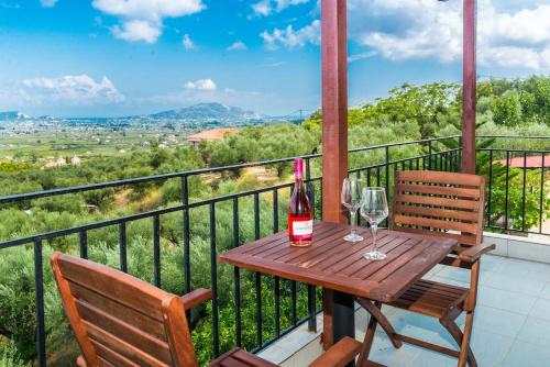 una mesa de madera con 2 copas de vino en el balcón en Sohoro house, en Fayiás