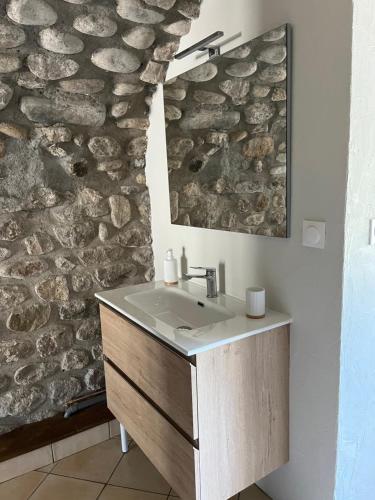 La salle de bains est pourvue d'un lavabo et d'un mur en pierre. dans l'établissement GITE DE LA CAPPELLA - CHAMBRE D'HÔTES A VOLTA, à Aubenas