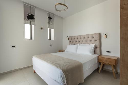 a white bedroom with a large bed and two windows at Mystic Garden Villas in Zakynthos Town