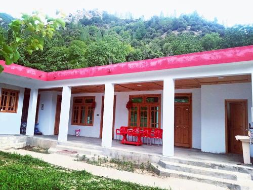 Tourist Guest House في Anīahgrām: منزل بسقف احمر وكراسي حمراء