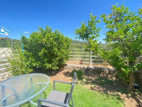 a table and chairs sitting in a yard with trees at מול האגם in Ma'alot Tarshiha