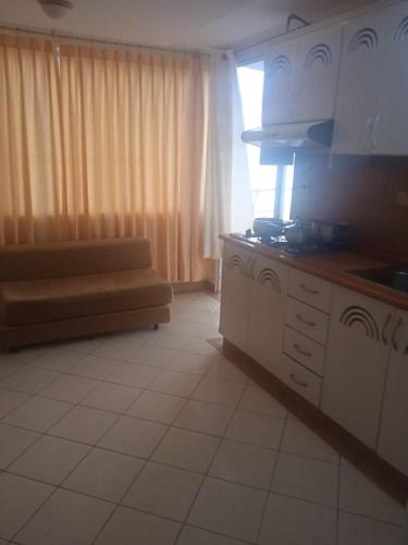 una cocina con armarios blancos y un sofá en una habitación en VACACIONES ARCO IRIS B−201, en Atacames