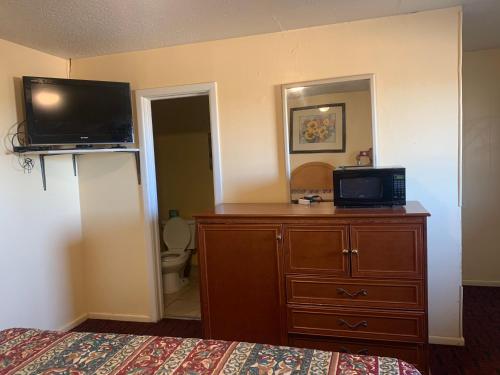 a bedroom with a bed and a dresser with a television on it at BUDGET INN in Big Spring