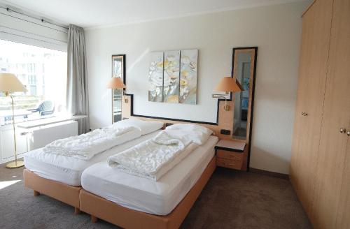 2 Betten in einem Zimmer mit 2 Lampen und einem Spiegel in der Unterkunft STRANDIDYLL, 134 - Typ B4 in Grömitz