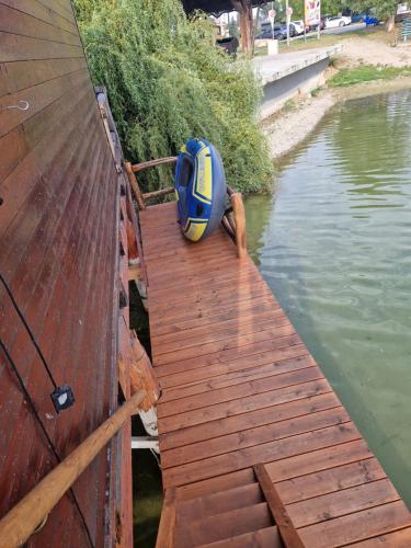 a wooden dock with a boat in the water at Houseboat Slnečné jazerá, apartmán 1 in Senec