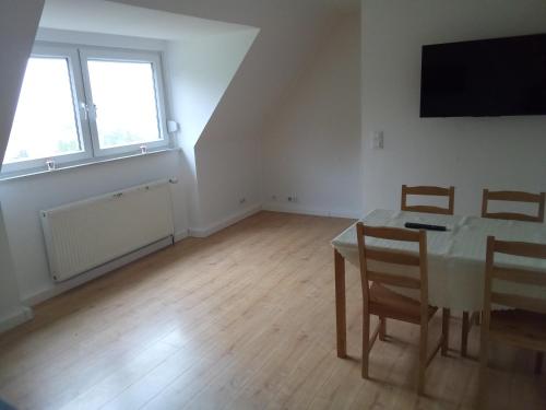 a dining room with a table and chairs and two windows at Haus am Mühlenkämpchen - Schönblick in Radevormwald