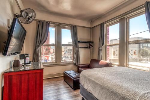 a bedroom with a bed and a chair and windows at Ram's Hotel in San Francisco