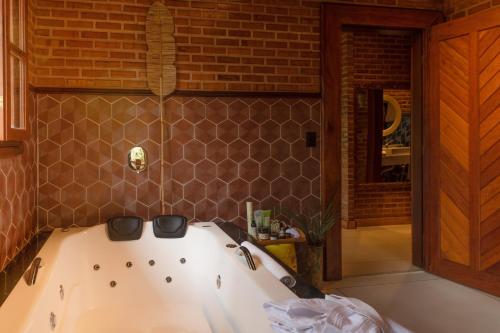 a bath tub in a bathroom with a brick wall at Embaúba Boutique Hotel in Teresópolis