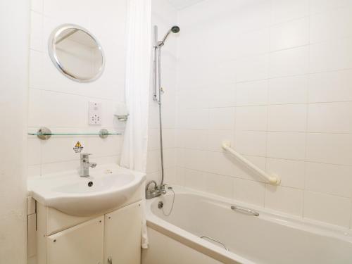 uma casa de banho com um lavatório, uma banheira e um espelho. em Flat 35 - Marine Court em Littlehampton
