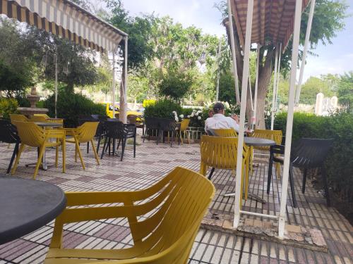 a man sitting at a table in a restaurant with yellow chairs at Hôtel Imilchil in Midelt